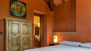 Une chambre à coucher avec un lit, une armoire en bois, un tableau et une table de chevet avec une lampe.