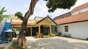 A courtyard with hexagonal paving, a tree, and potted plants. - Hotel O Wallet Family Residence Syariah (Lumajang)