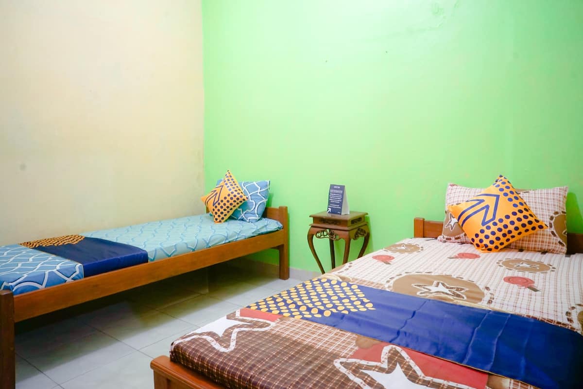 A bedroom with two wooden beds, each with patterned bedding and pillows.