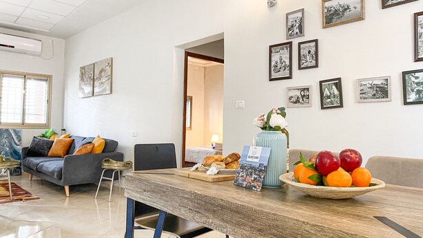 Een moderne woonkamer met een eettafel, banken en een muur versierd met ingelijste foto’s.