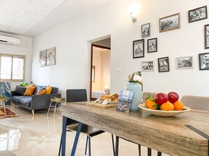 A modern living room with a dining table, sofas, and a wall adorned with framed pictures. - Modern Downtown 3BR by Ahlan Hospitality (Nazareth)