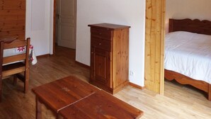 Una habitación con una cama, cómoda, silla y mesa de madera.