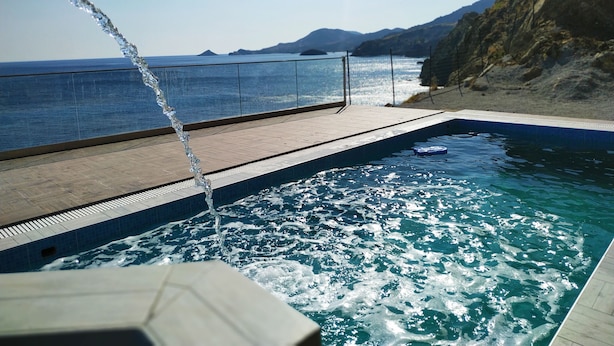 A pool with clear blue water, a tiled deck, and a view of the sea and distant mountains. - Luxurious Villa Paradise PRIVATE BEACH (Faistos)