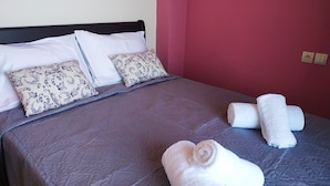 A neatly made bed with a patterned bedspread, two decorative pillows, and rolled towels on the bed. - Luxurious Villa Paradise PRIVATE BEACH (Faistos)