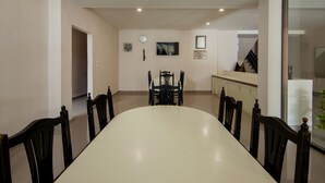 A dining area with a long table and chairs, a clock, and a framed picture on the wall. - OYO 2382 Wisata Hotel (Samosir)
