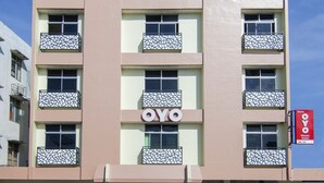 A building with a 'OYO' sign, multiple balconies with geometric patterns, and a clear sky. - OYO 2382 Wisata Hotel (Samosir)