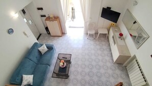 A modern living room with a blue sofa, a coffee table, and a TV on a white cabinet. - Ischia Ponte Romantic Apartment in the Historical Center and Near the sea (Ischia)