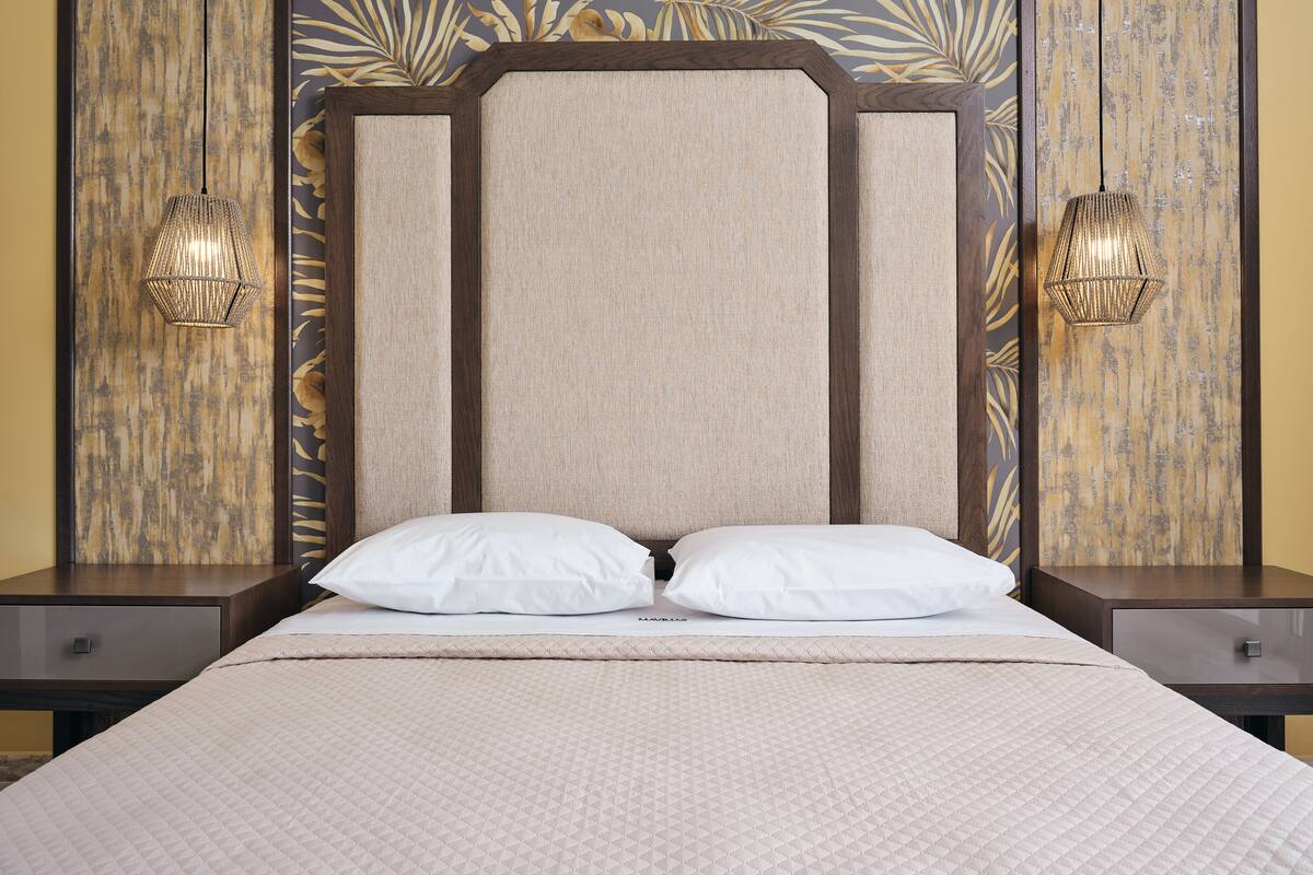 A bed with a headboard, two bedside tables, and wall-mounted lamps.