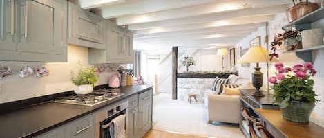 A modern kitchen with grey cabinets, a wooden countertop, and a dining area with a table and chairs.