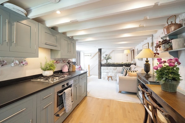A modern kitchen with grey cabinets, a wooden countertop, and a dining area with a table and chairs.