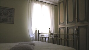 A bedroom with a bed, a window with curtains, and a door with paneling. - Villa Al Mare Rimini (Rimini)