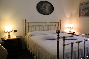 A bedroom with a bed, two bedside tables, and a wall-mounted painting. - Villa Al Mare Rimini (Rimini)