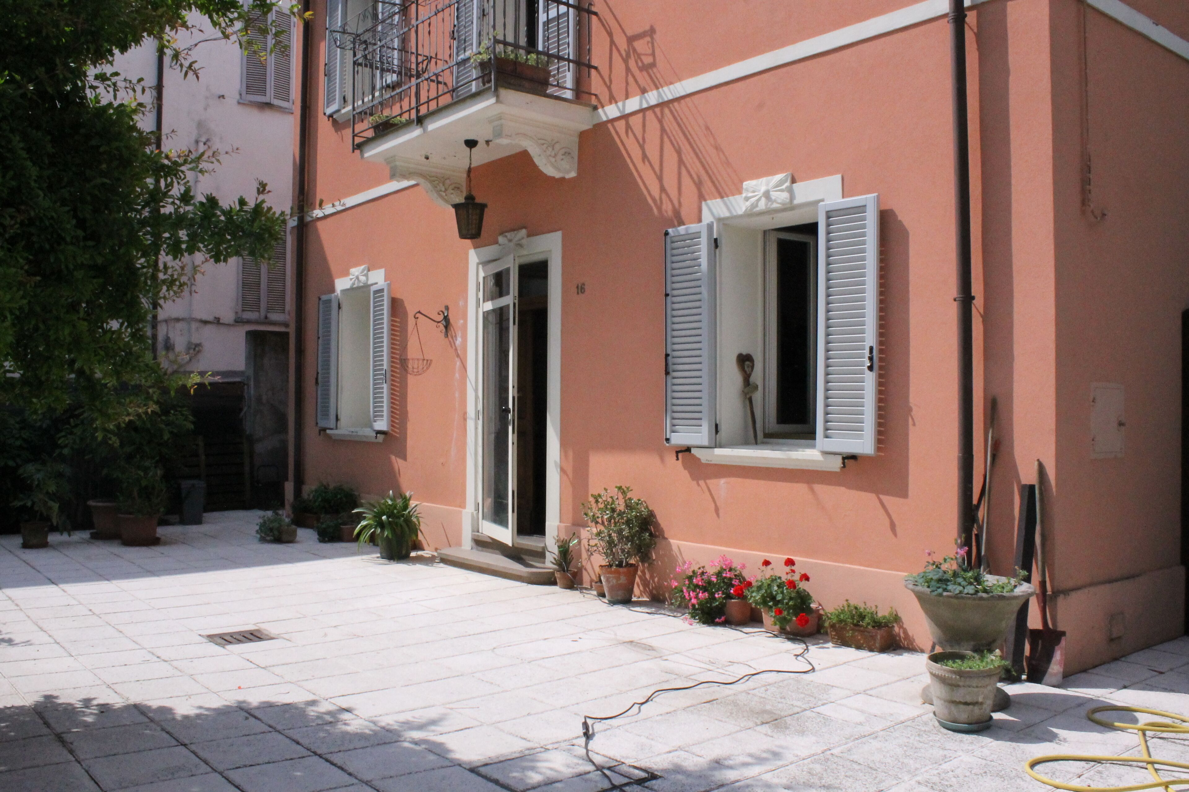A building with a balcony, potted plants, and a door.