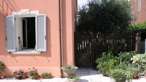 A courtyard with potted plants, a wooden fence, and a building with a window. - Villa Al Mare Rimini (Rimini)