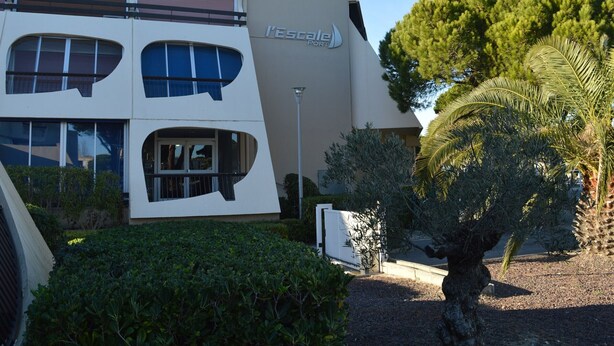 Un edificio moderno con un diseño arquitectónico único, con ventanas amplias y un llamativo letrero 'l'Escalier'.