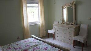 Una camera da letto con un letto, una cassettiera, una sedia e una finestra con tende.