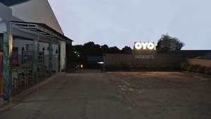 The entrance to the OYO Intan Motel with a sign, a paved driveway, and a building with a sloped roof.