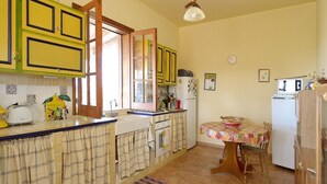 A compact kitchen with yellow cabinets, a dining table with a floral tablecloth, and a refrigerator.