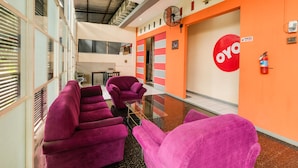 A hotel corridor with purple armchairs, a glass table, and a large 'oyo' logo on the wall. - Hotel O Camel Residence (Semarang)