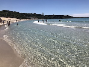 A beach with clear water, sandy shore, and a forested hill in the background. - La Maison de Medea Salento (Pulsano)