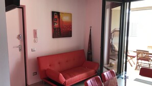 Ein modernes Wohnzimmer mit einem roten Sofa, einem Glastisch und einem Bild an der Wand.