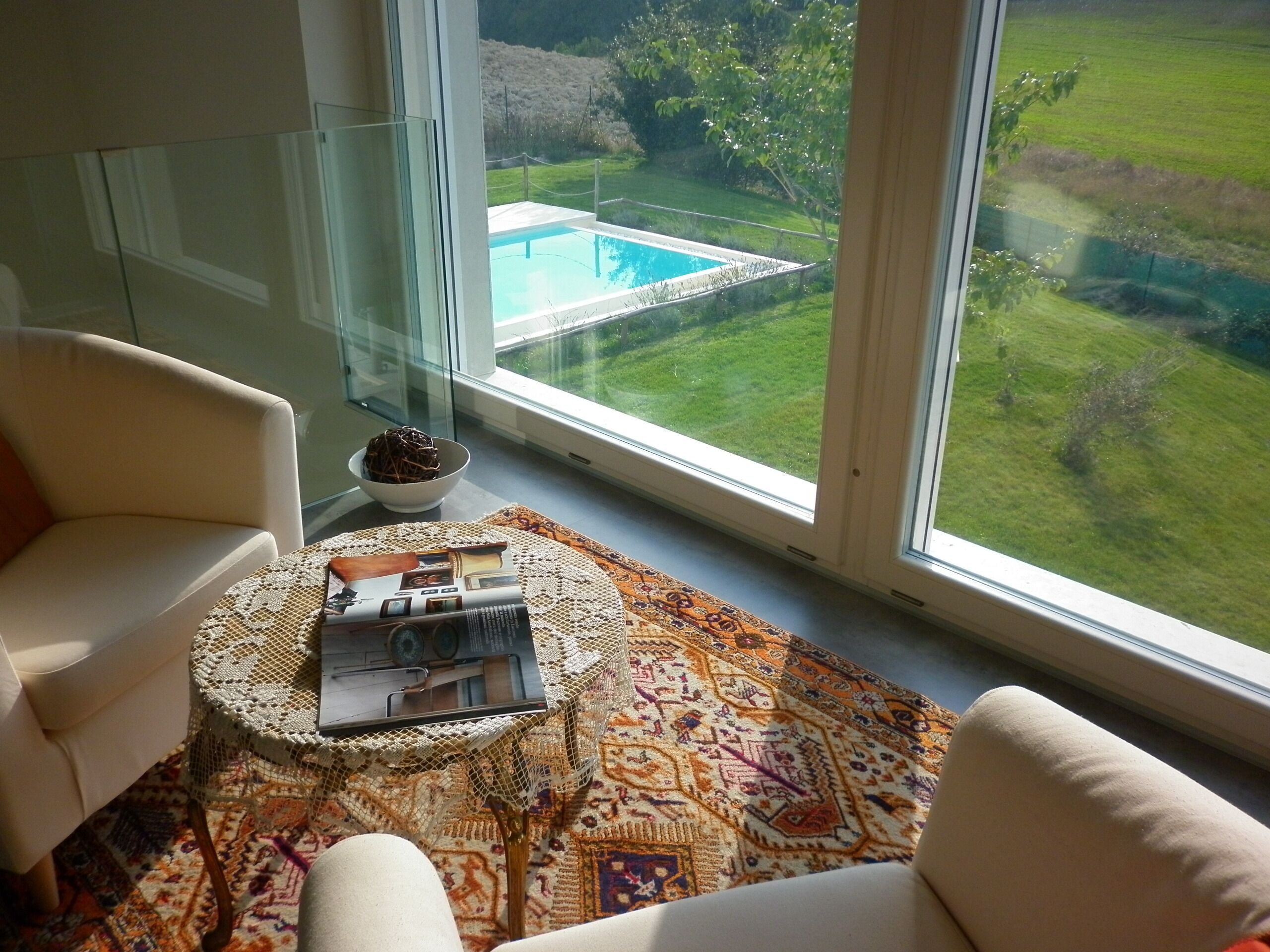 Una sala de estar moderna con un ventanal, vista a la piscina y un rincón de descanso acogedor.