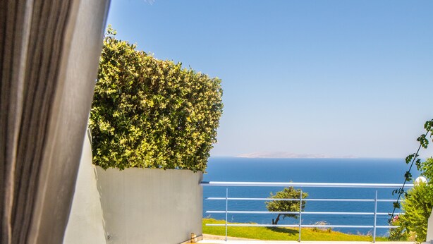A patio with a round table and two chairs, a potted plant, and a view of the sea. - Luxurious Villa Ariadni Theseus Crete (Malevizi)