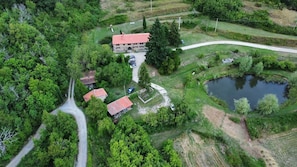 An aerial view of a property with a main building, a pond, and a winding road.
