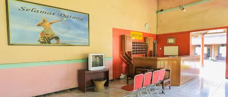A reception area with a television, a "SPOT ON" sign, and a poster of a person with a bow.