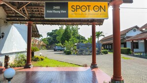 A hotel entrance with a sign for 'Hotel Raung View' and 'SPOT ON' indicating an affordable and convenient hotel.
