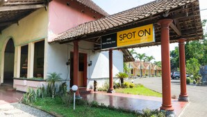 A hotel entrance with a sign reading "2465 Hotel Raung View" and "SPOT ON AFFORDABLE AND CONVENIENT HOTEL".