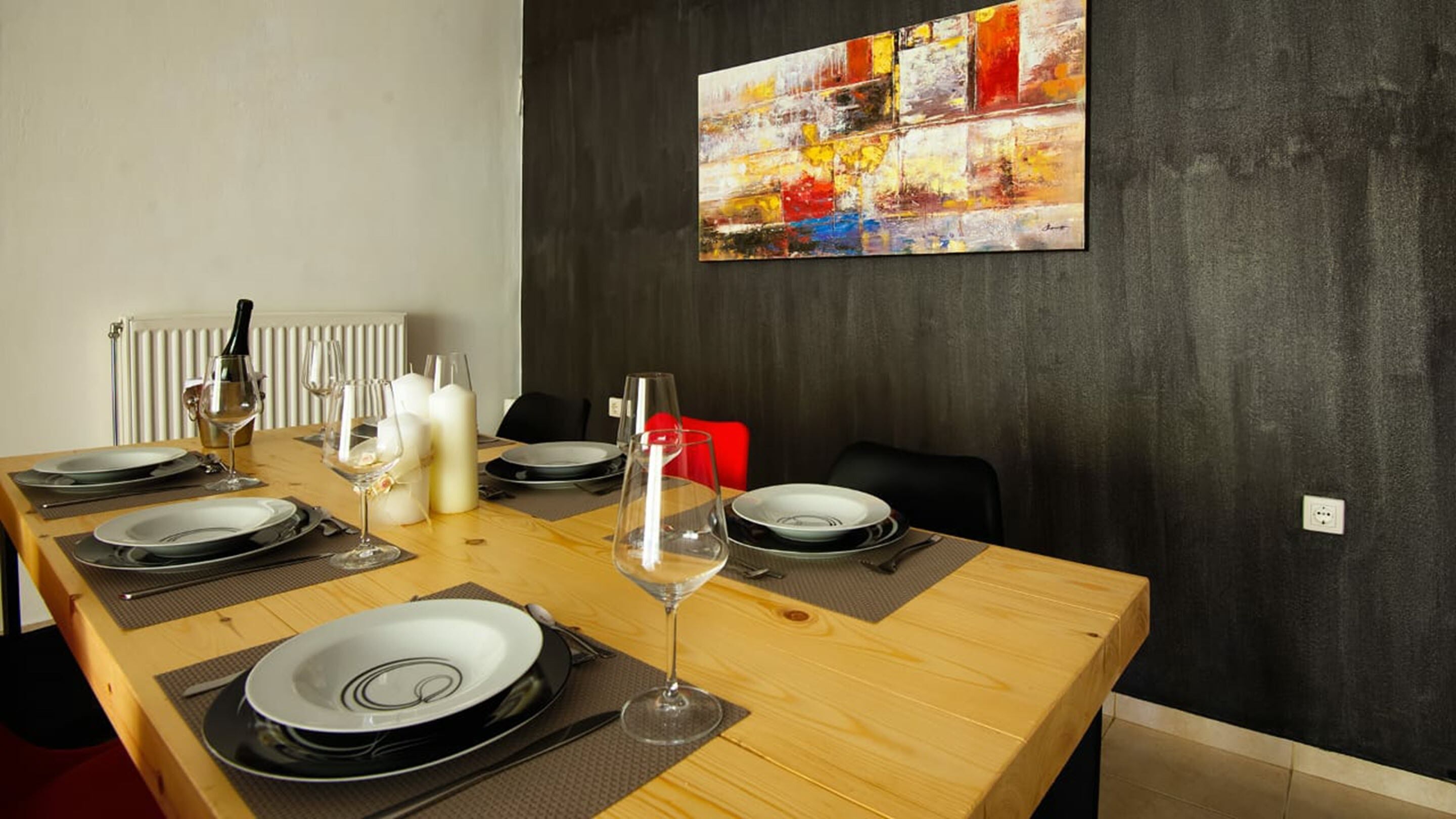 A dining room with a long wooden table set for a meal, featuring plates, glasses, and candles.