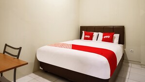 A neatly arranged hotel room with a bed, a small table, and a chair. - OYO 2354 3 Point Residence (Surabaya)