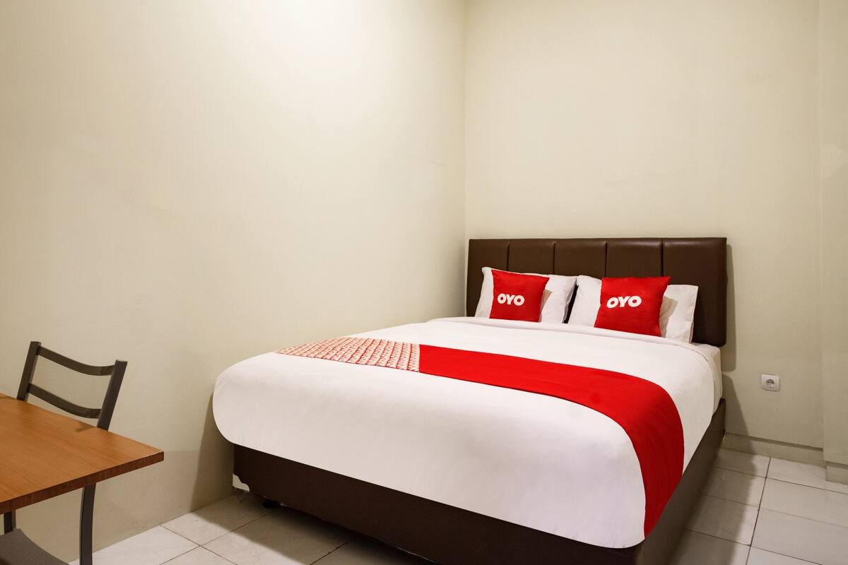 A neatly arranged hotel room with a bed, a small table, and a chair.