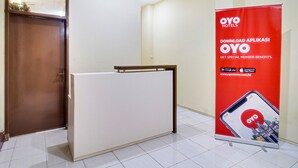 A reception desk with a red promotional banner for OYO Hotels. - OYO 2354 3 Point Residence (Surabaya)