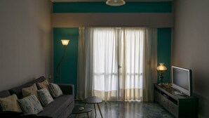 A modern living room with a sofa, television, and floor lamp. - Cozy Flat Kika's Heraklion CITY CENTRAL (Heraklion)