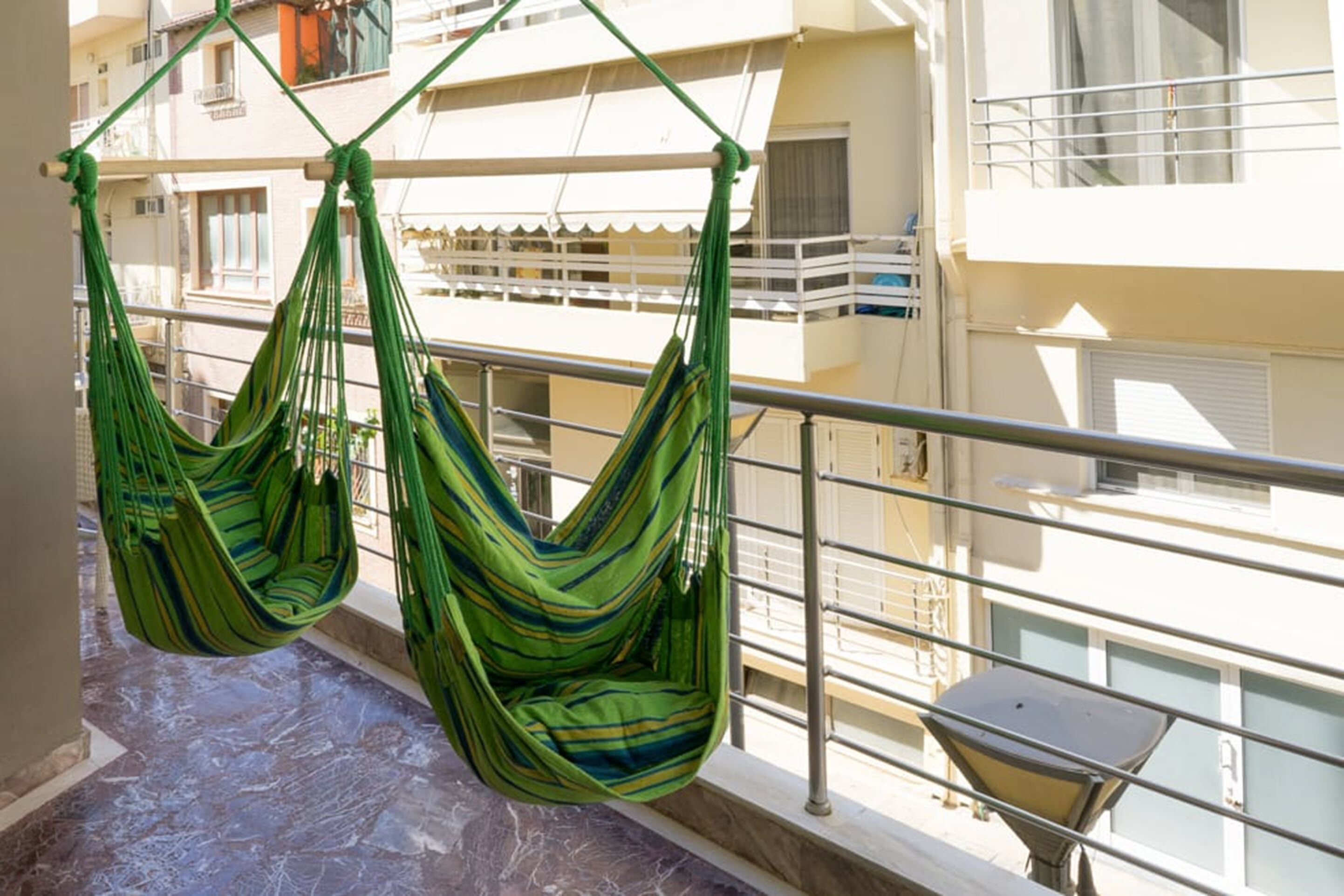 Two green hammocks hanging on a balcony railing.