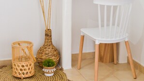 A white desk with a mirror, a white chair, a woven basket, a wicker vase with pampas grass, and a small potted plant. - Avgerinos Deluxe Rooms (Milos)