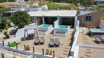A rooftop pool area with lounge chairs and a hot tub.