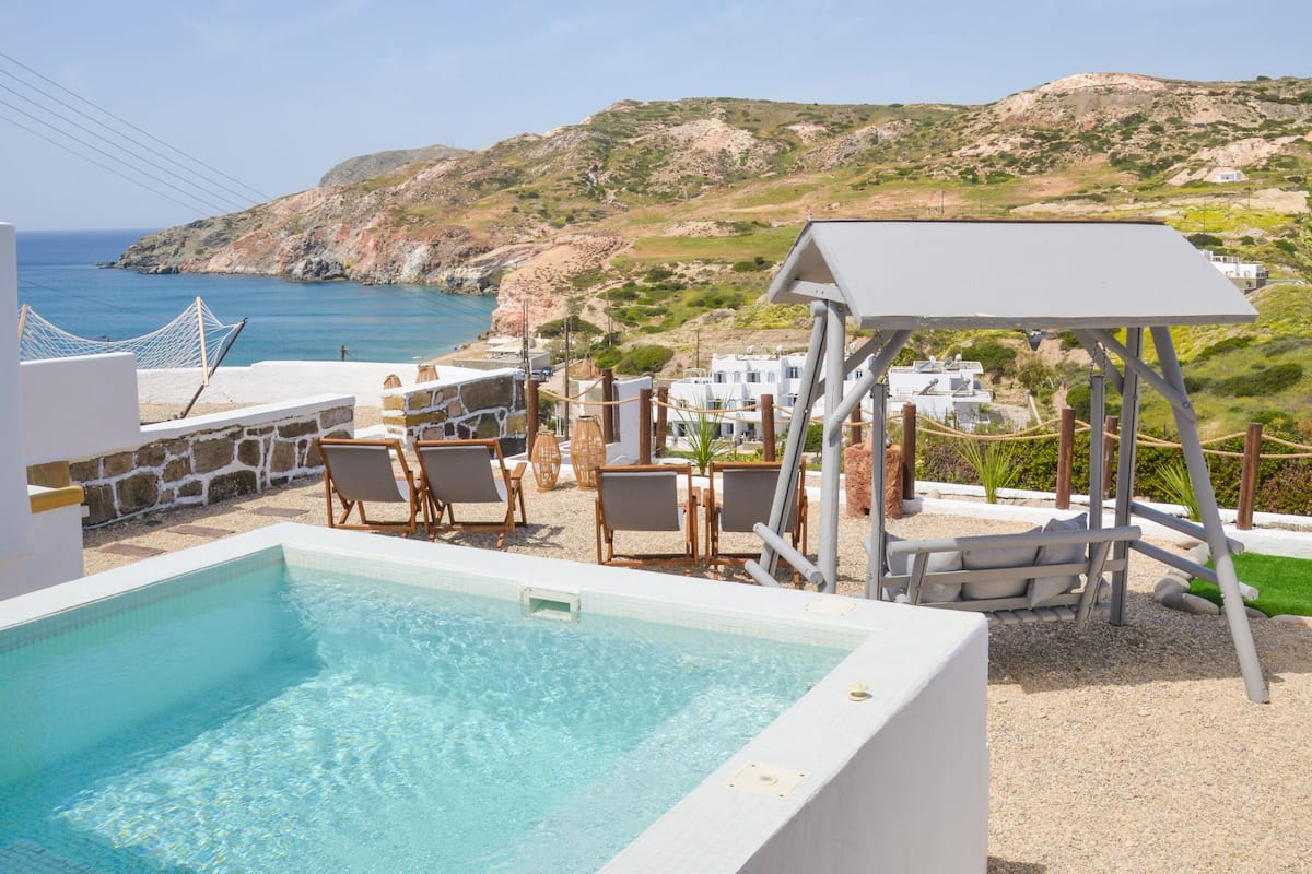 Un espace piscine avec une eau d’un bleu limpide, des chaises longues et une vue sur la mer et les collines.
