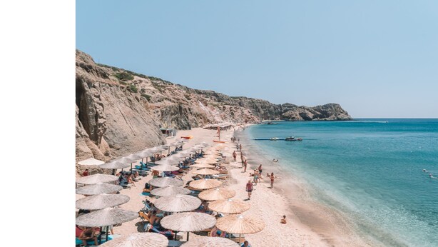 A beach with umbrellas and people. - Avgerinos Deluxe Rooms (Milos)