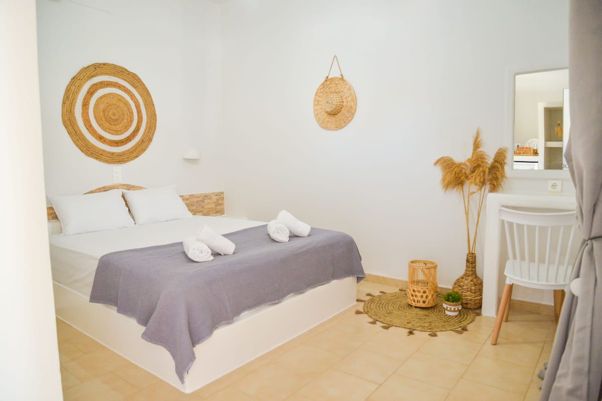 Une chambre à coucher bien rangée, avec un lit, une table de chevet, une chaise et des objets décoratifs.