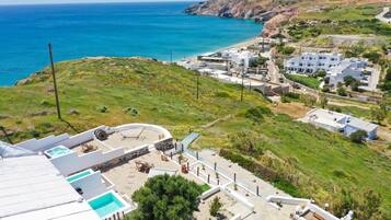 A coastal property with a pool area, a view of the sea, and a hilly landscape.