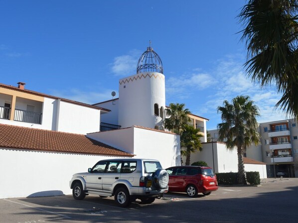 A building with a white facade, a red-tiled roof, and a cylindrical tower with a blue dome. - Seafront apartment with pool, sleeps 6, pets allowed (Saint-Cyprien)