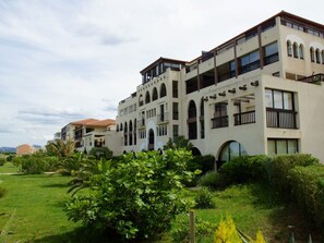 A multi-story hotel with balconies, arched windows, and a landscaped garden. - Seafront apartment with pool, sleeps 6, pets allowed (Saint-Cyprien)