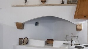 Una cocina con horno empotrado, encimera blanca y estantes con diversos utensilios de cocina.