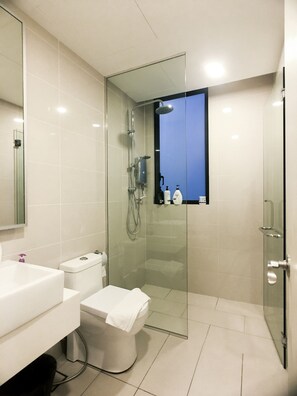 A modern bathroom with a glass-enclosed shower, a white sink, and a toilet.