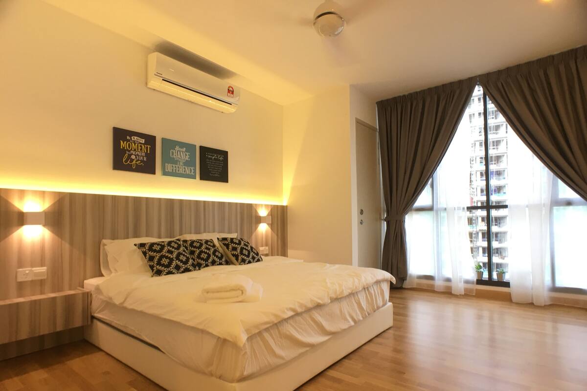 A modern bedroom with a large bed, an air conditioning unit, and motivational wall art.