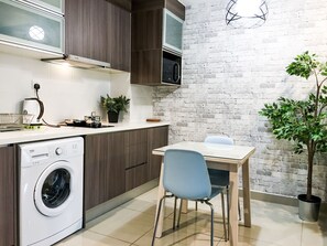 A compact kitchen with a washing machine, a microwave, and a dining area with a table and chairs.