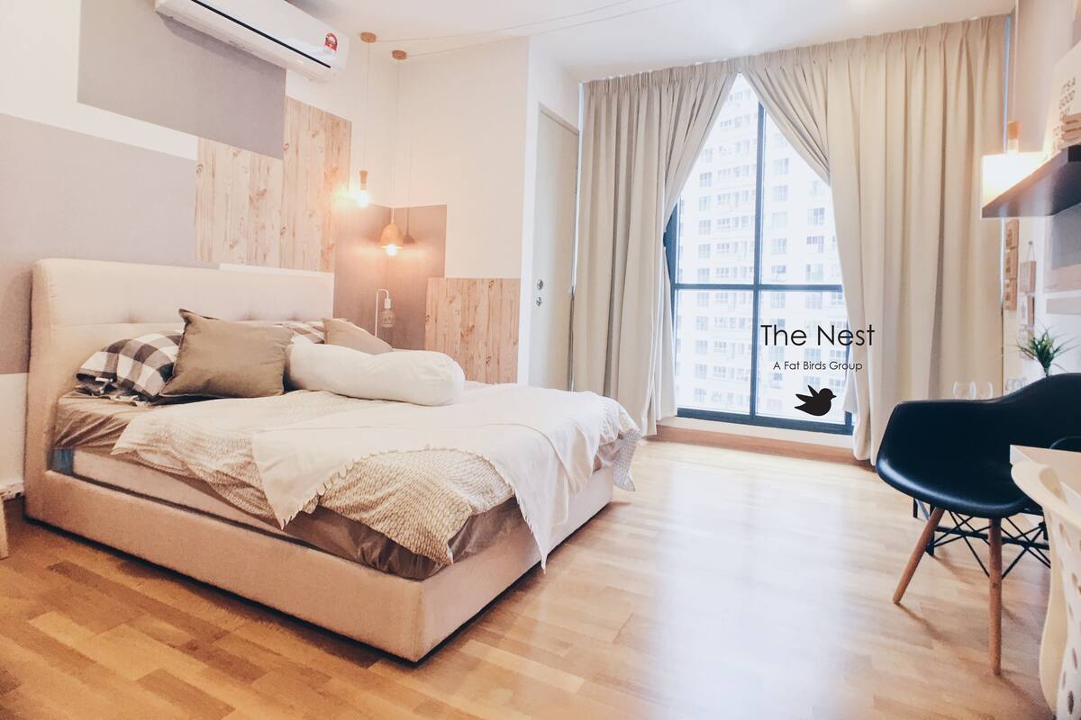 A modern bedroom with a large bed, a desk, and a window with curtains.